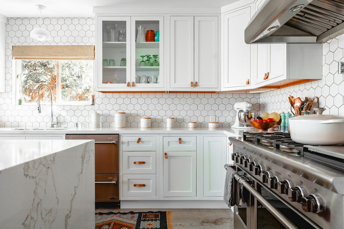 Bright kitchen with white shaker cabinetry, a quartz waterfall island, hexagon tile backsplash and a professional-style range